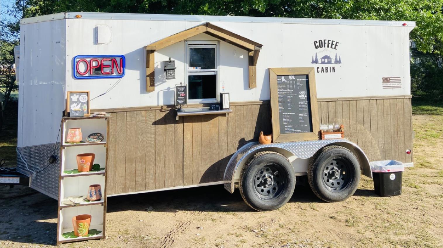 Photo of stolen trailer. Trailer is pictured with Coffee Cabin logo on the front, a menu, and an OPEN neon sign with touches of cabin trimmings. 